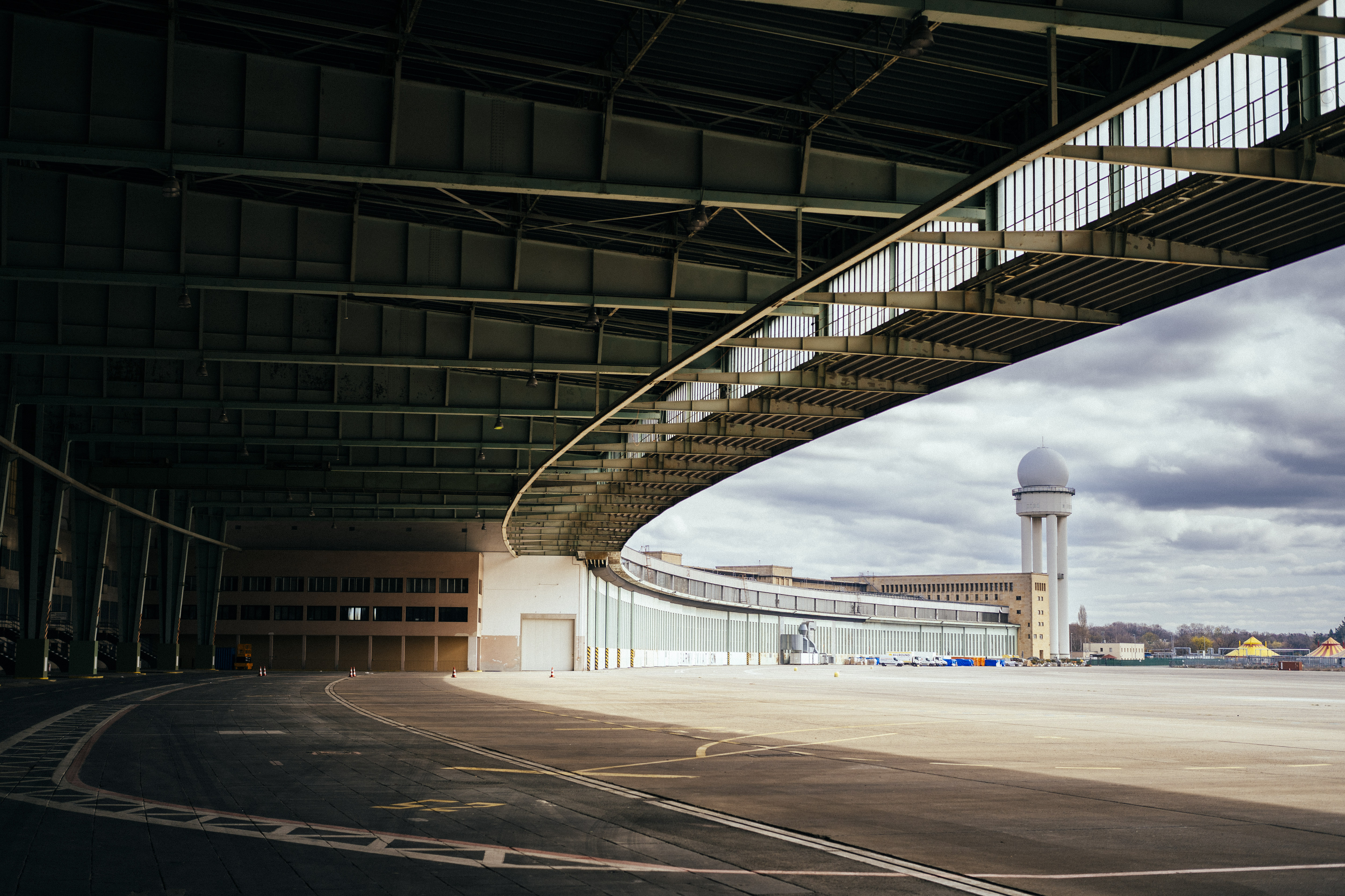 The wide outdoor area of an airport, with an arched fly over structure, and a sphere-topped tower, seen from below.