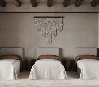 A bedroom with concrete wall and a macramé curtain
