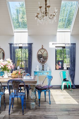 dining table with blue chairs and blue curtains with chandelier above table