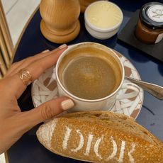 Hand with light brown nails holding a coffee cup