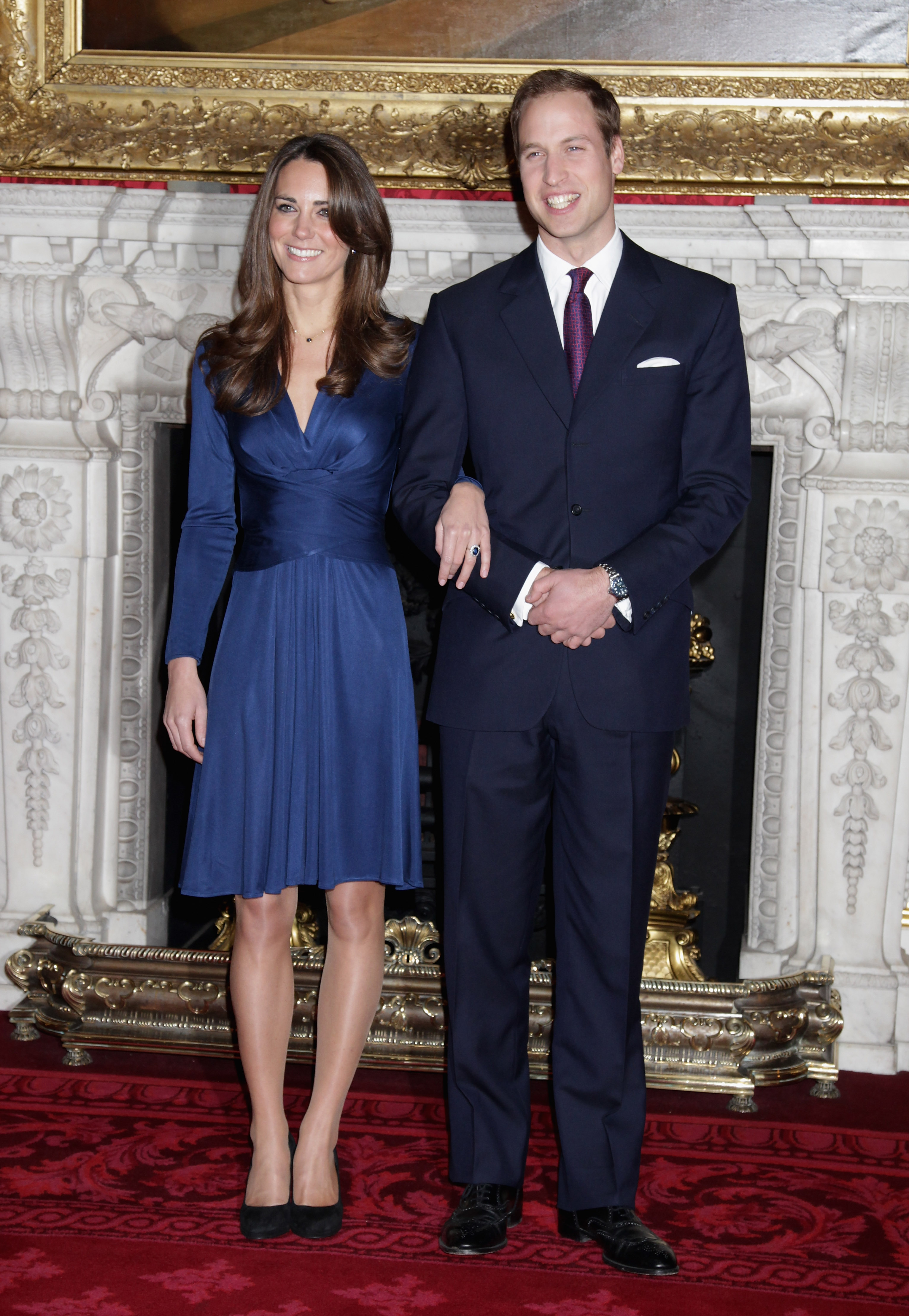 Kate Middleton and Prince William smiling with their arms linked during their engagement interview