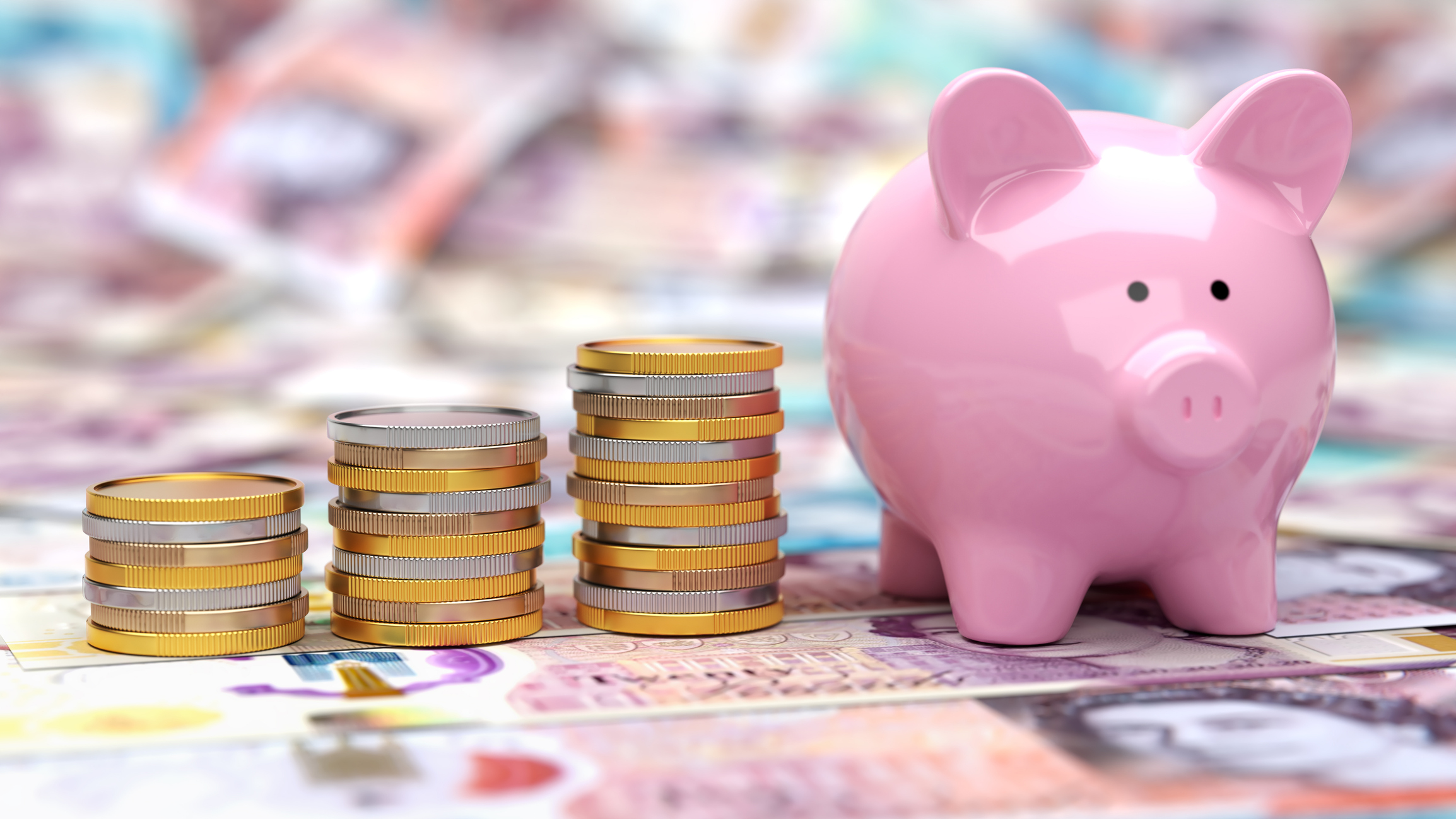 Piggy Bank with stacks of coins on British pound banknotes representing cash savings
