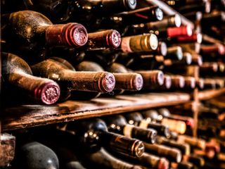 Old and dusty bottles of wine on wooden storage rack