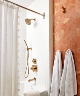 A bathroom with white ceramic tiles around the shower area paired with handmade clay tiles elswhere