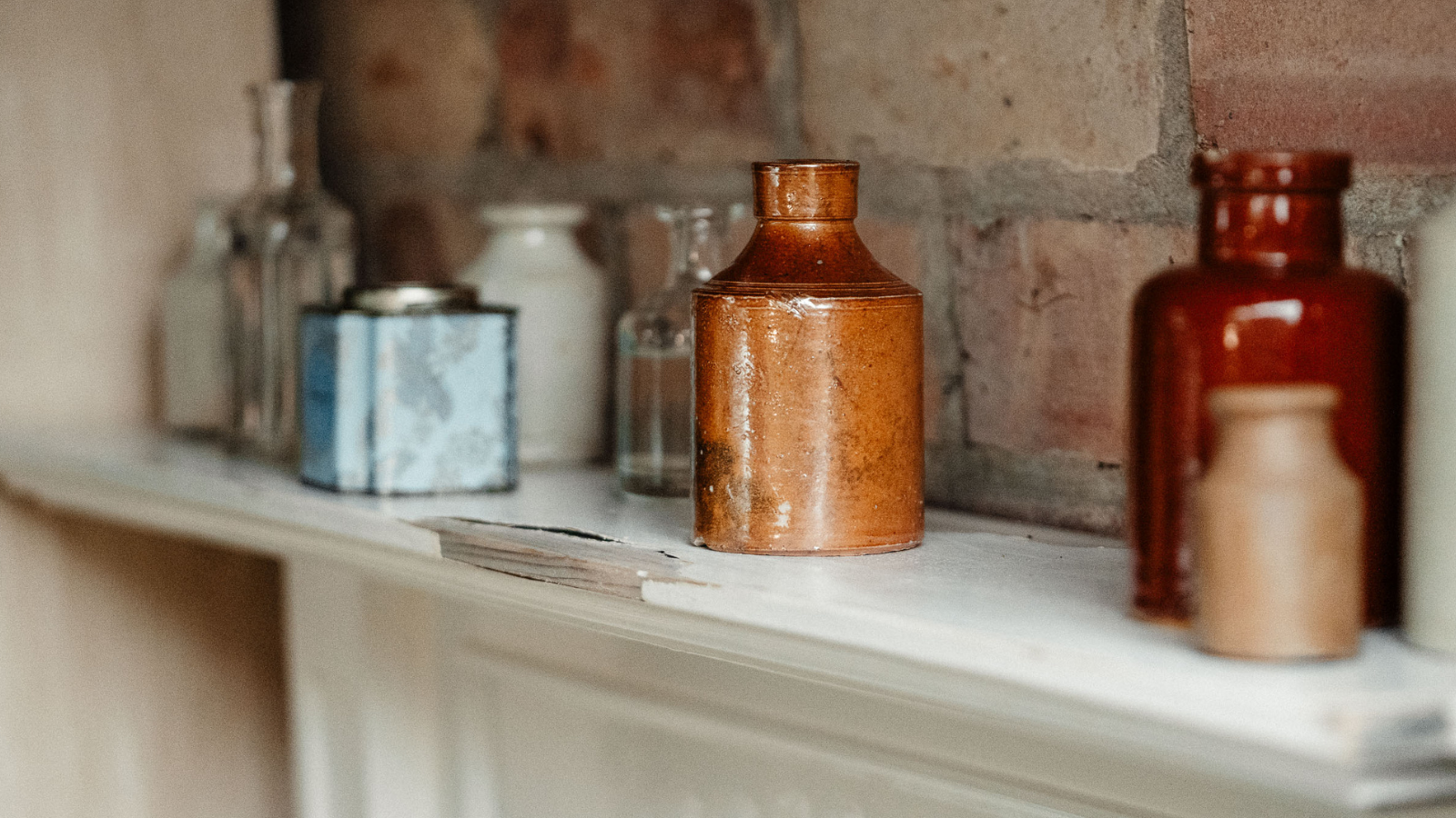 mantelpiece with rustic ceramic ink wells and tins