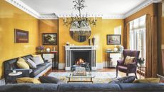 Living room decorated in yellow with coving, wooden flooring with a grey and yellow rug with grey sofas. A redesigned and renovated London townhouse, home of Mikael Lofberg and his partner.
