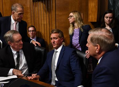 Senate Judiciary Committee member Senator Jeff Flake (R-AZ) (C) speaks with colleagues after a hearing on Capitol Hill in Washington, DC on September 28, 2018.