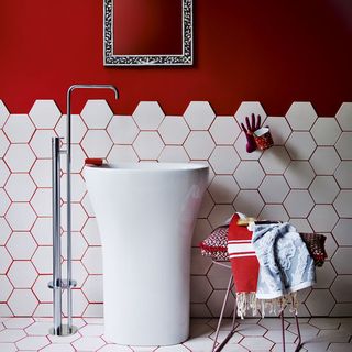 bathroom with red wall and honeycomb shape tiles and washbasin