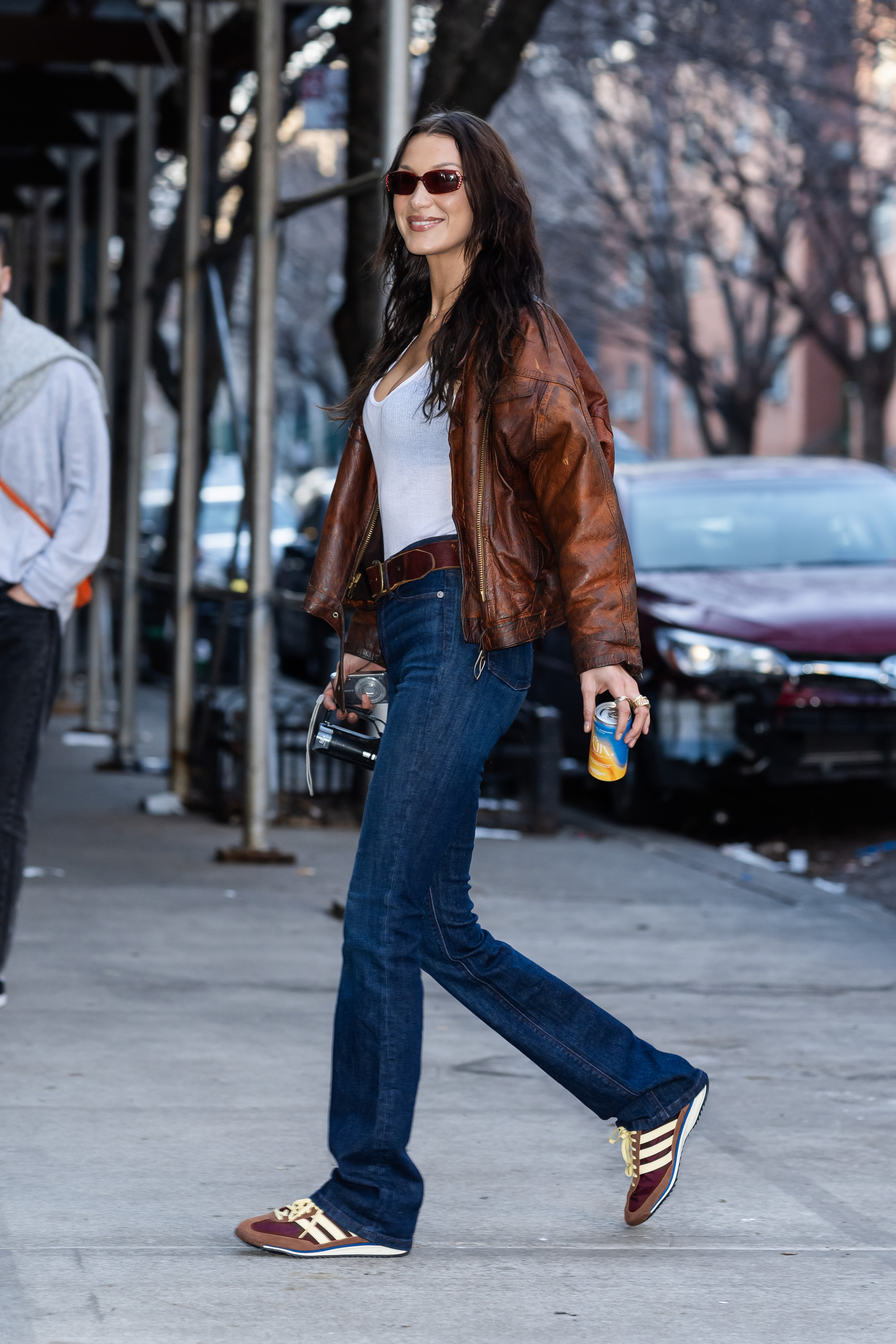 Bella hadid wear white shirt, brown bomber jacket, blue jeans , brown sneakers