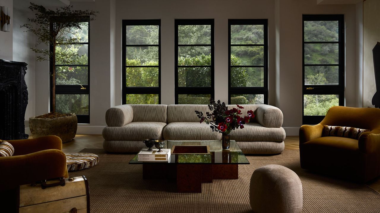 large living room with central gray sofa and big windows