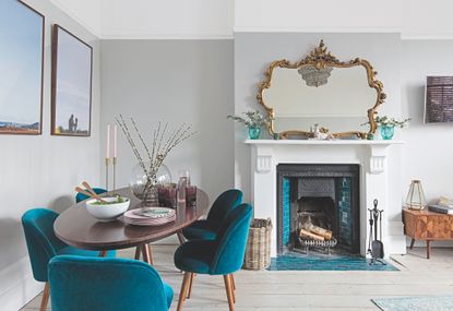Fireplace with blue tiles surrounded by white mantlepiece, in a grey and white living room