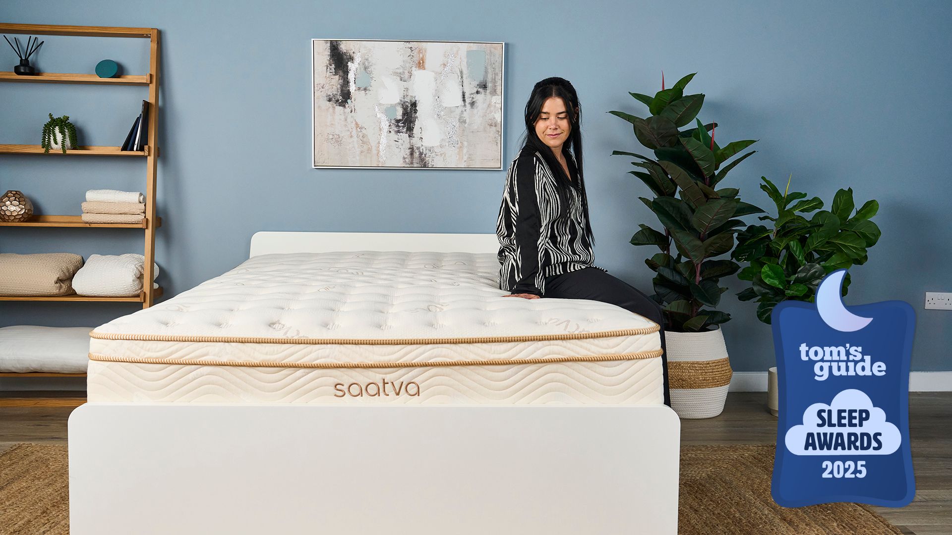 A Tom's Guide Sleep Writer, Eve Davies, sat on the edge of the Saatva Classic, the winner of the Tom's Guide Best Luxury Mattress award, feeling the surface of the mattress and smiling.