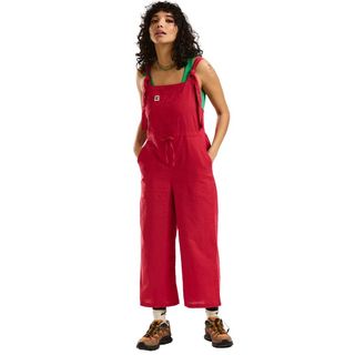 A woman wears a red linen pair of dungarees.