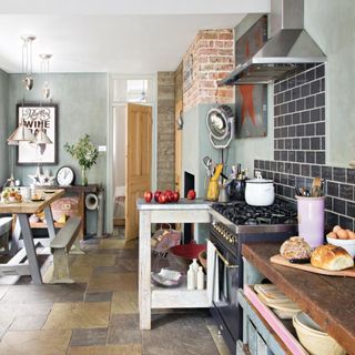 kitchen with green walls, floor lamp, wooden table and worktop and stone flooring