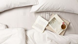 Neutral best sheets on bed with books and mug of warming tea