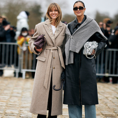 two guests attend paris fashion week spring summer 2025 wearing beige and grey coats holding bags 