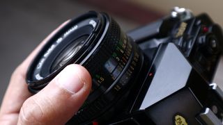 A hand holding the lens of a film camera