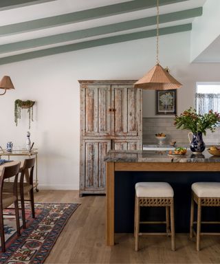 transitional kitchen with vintage hutch for housing appliances and a navy kitchen island