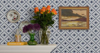 How to wallpaper, with a diamond print blue and white design hung above a fireplace, with plates and a painting mounted on the wall.