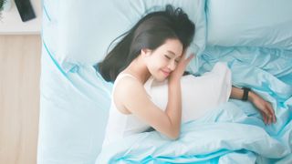 Woman asleep in bed wearing smartwatch