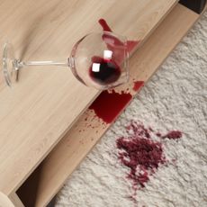 Red wine spilt over wooden table and cream rug