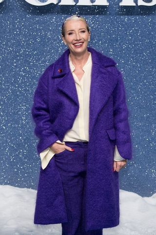 Emma Thompson wearing a purple coat and trousers