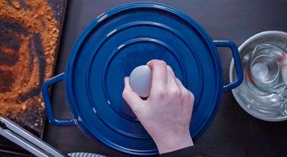 Woman removing lid from a blue Dutch oven