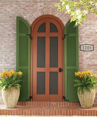 curved terracotta front door with green shutters