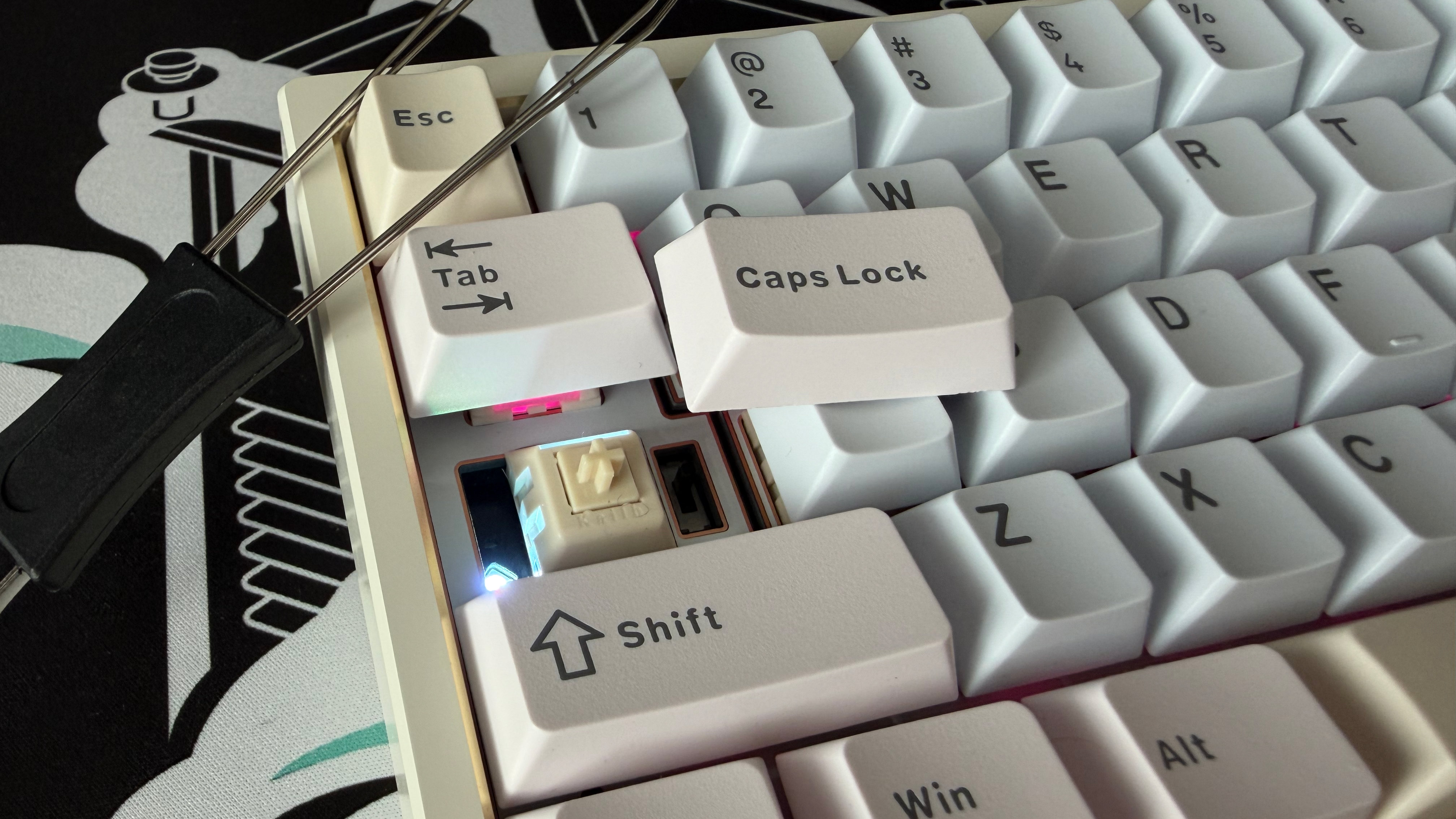 A closeup of the Wobkey Zen 65 Ultra, showing the Caps Lock key remove, the switch and On/Off switch beneath and the keycap removal tool.