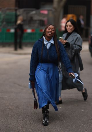 woman wearing cowboy boots, sweater, button-down shirt, and skirt