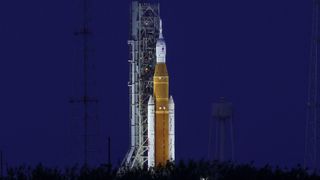 a large orange rocket on a launch pad at night