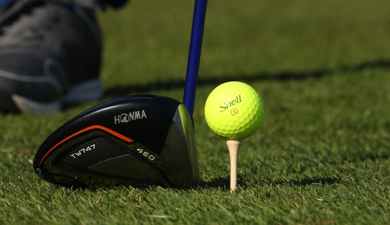 Snell Get Sum Golf Ball is on a tee, with a driver placed behind it