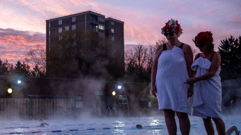 Swimmers stand next to the pool at Charlton Lido which has reopened under the UK's tier system.