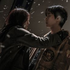 Han So-hee (as Yoon Chae-ok) rests her hand on Park Seo-jun's (as Jang Ho-jae) shoulder as it snows, in Gyeongseong Creature S2.