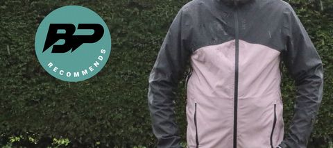 Man wearing cycling jacket in front of hedge