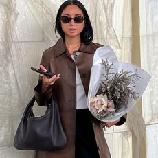 influncer Jordan Risa posing in a brown leather jacket and a bunch of flowers