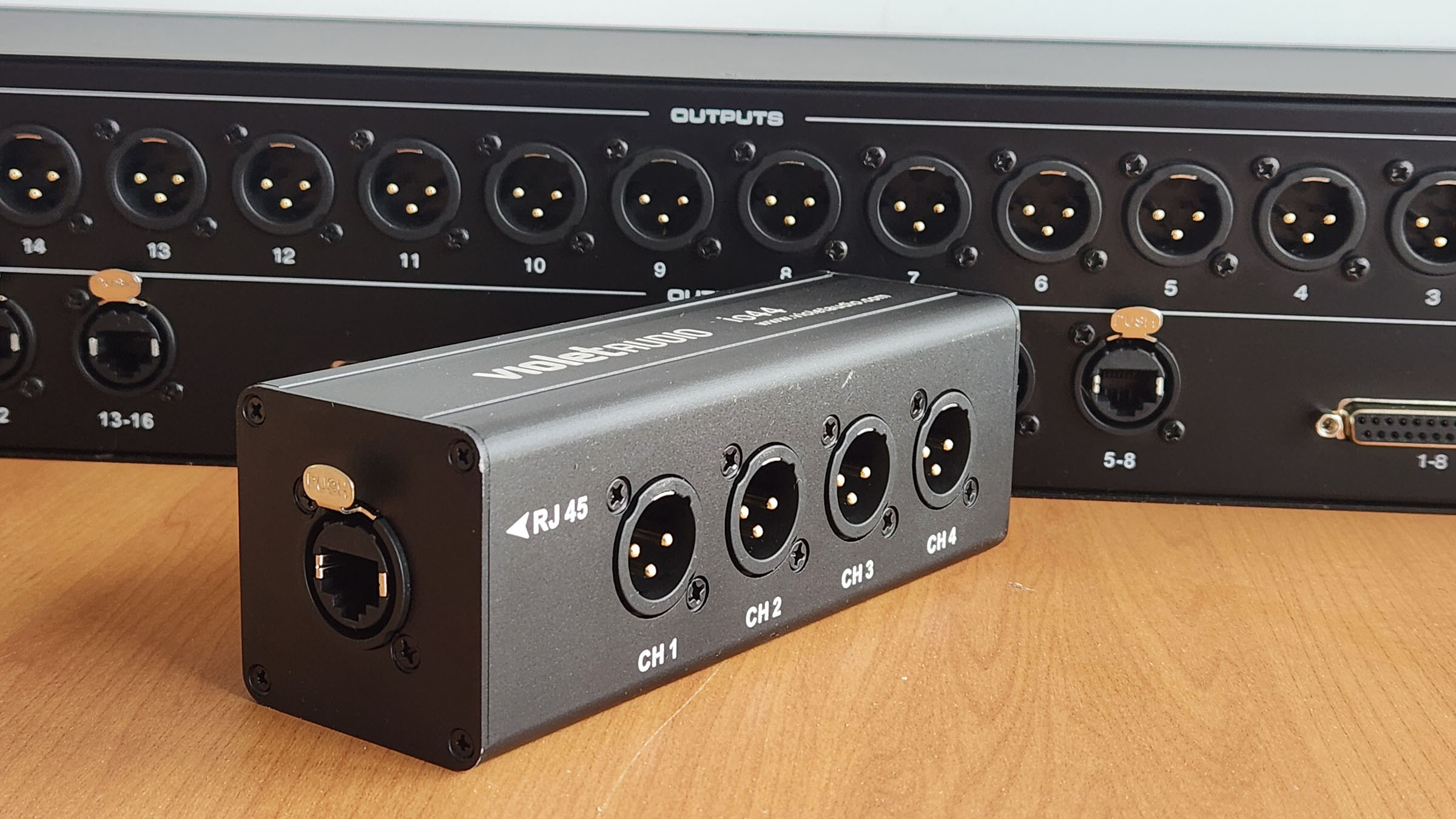 The Violet Audio io44 four-channel XLR-to-Ethercon adapter (foreground) and the DX16B 16-channel passive audio splitter (behind).