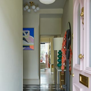 A light green-painted hallway with a pastel pink front door