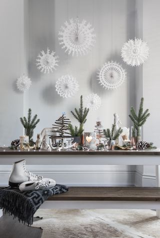 a white dining room with Christmas table decor and small fir trees