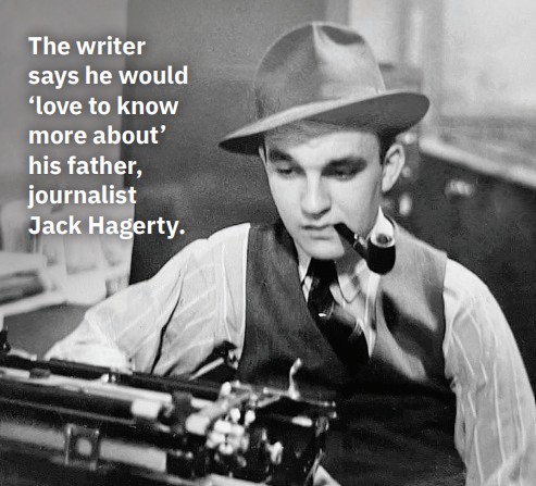 A black and white photo of the author's father, Jack Hagerty. He is smoking a pipe, wearing a reporter's hat and in front of a manual typewriter.