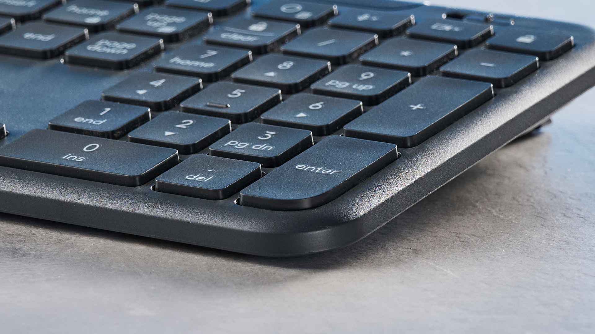 The Logitech K620 keyboard in a graphite grey colorway photographed as part of the MK625 como on able and white background.