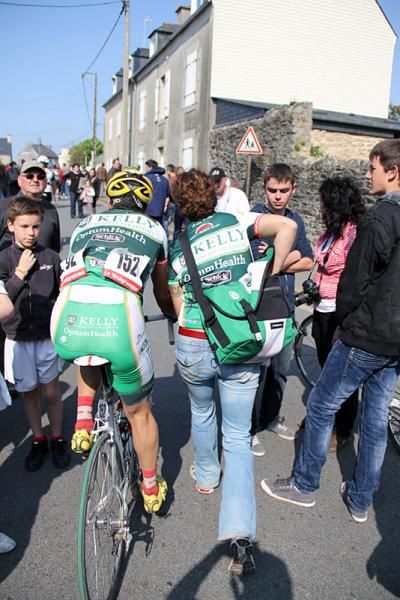 Alex Candelario and soigneur Ryan Kelly maneuver through the thick crowds in Lannais.