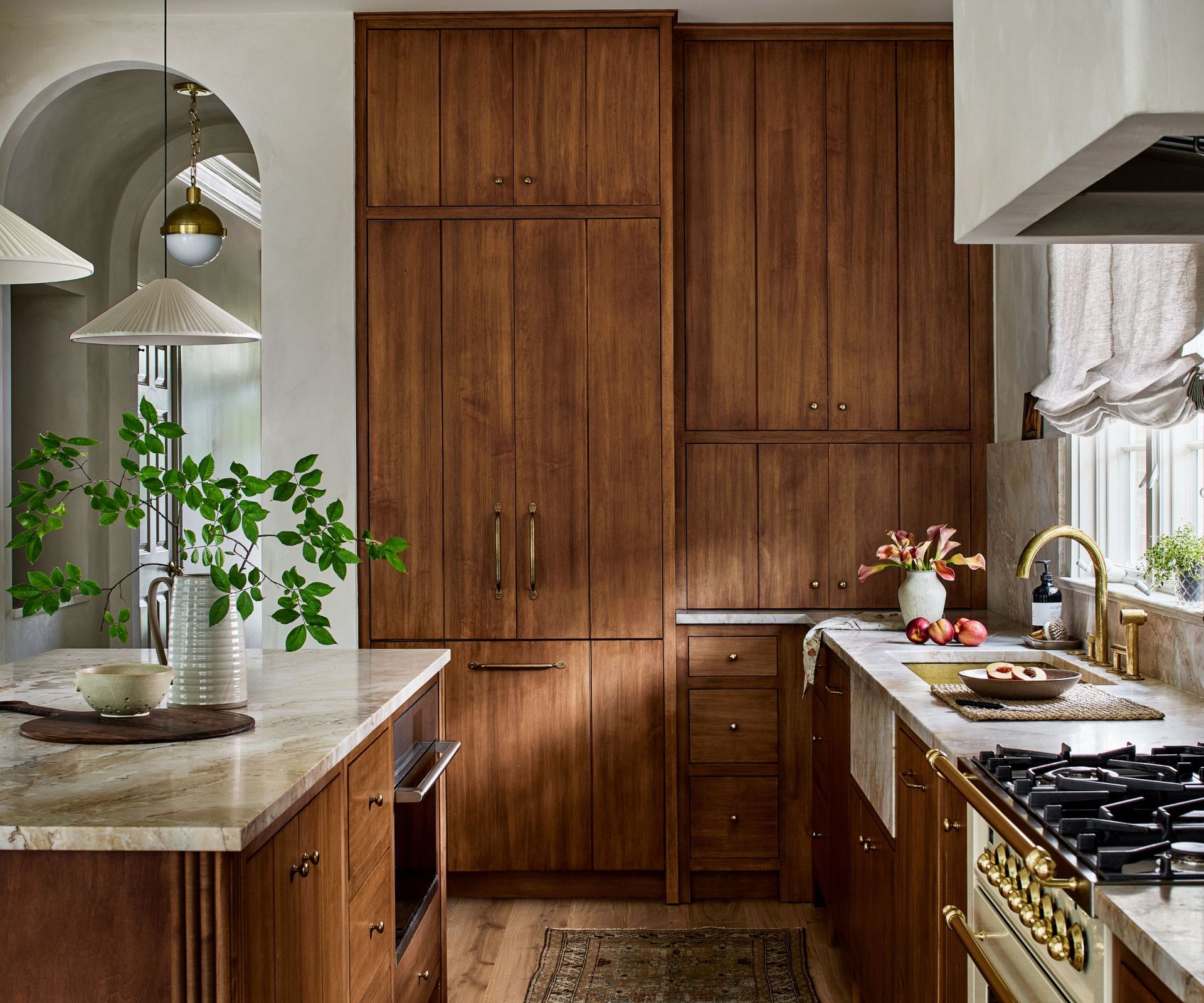 A kitchen with wood cabinets and marble countertops for a Japandi feel