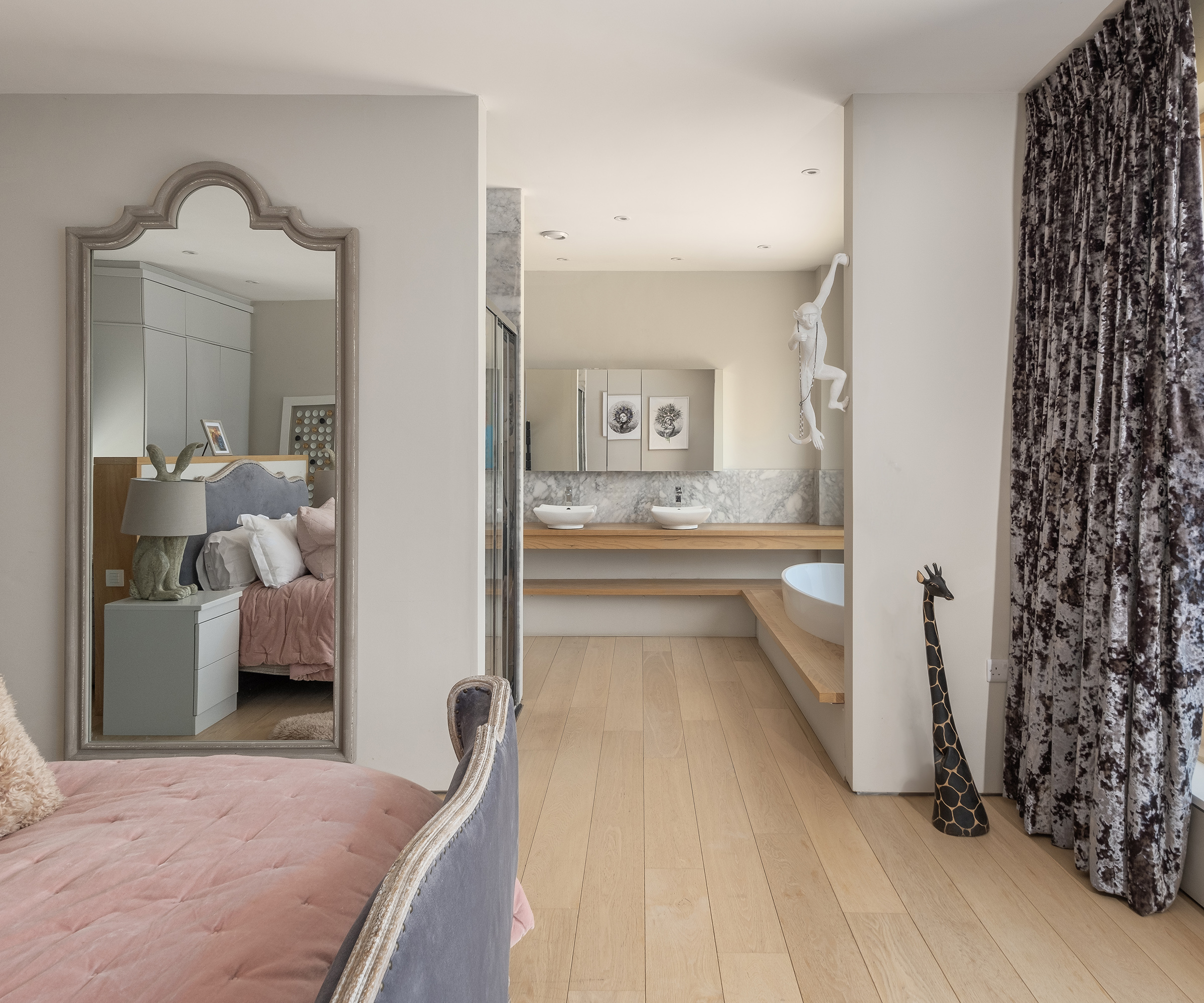 A large bedroom with en en-suite open plan bathroom with double sinks