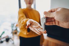 Close-up shot of a real estate agent giving a young Asian woman the keys to her new home