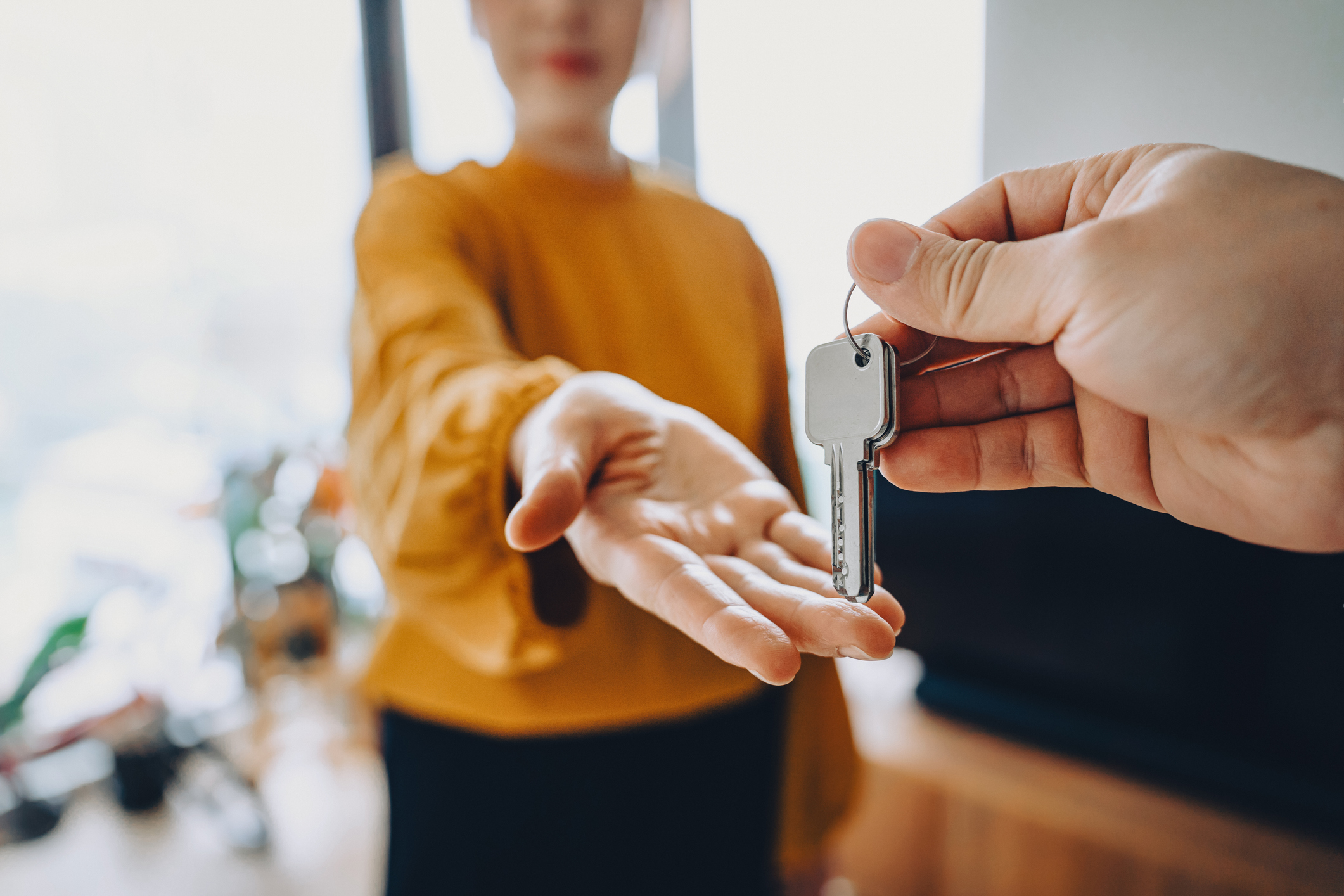 Close-up shot of a real estate agent giving a young Asian woman the keys to her new home