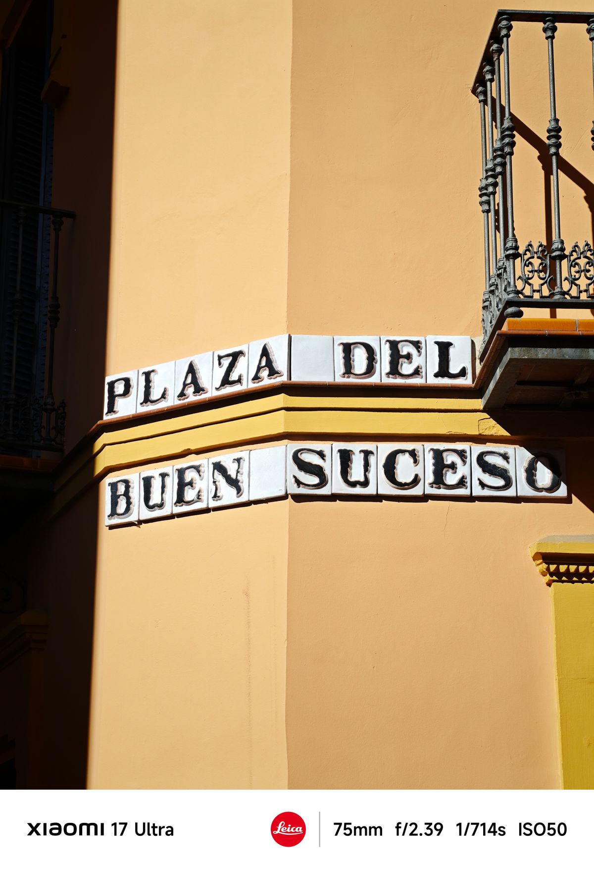 Corner of a yellow building with ceramic street sign reading &ldquo;Plaza del Buen Suceso&rdquo; and wrought-iron balcony above.