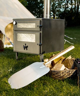 a wood burning stove next to a tent with a pizza stone