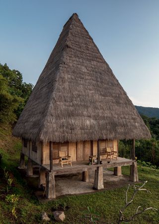 A home build with timber and straws featuring a cone shaped roof and elevated by 12 timber legs as the base. Located on the mountains with views of the forest