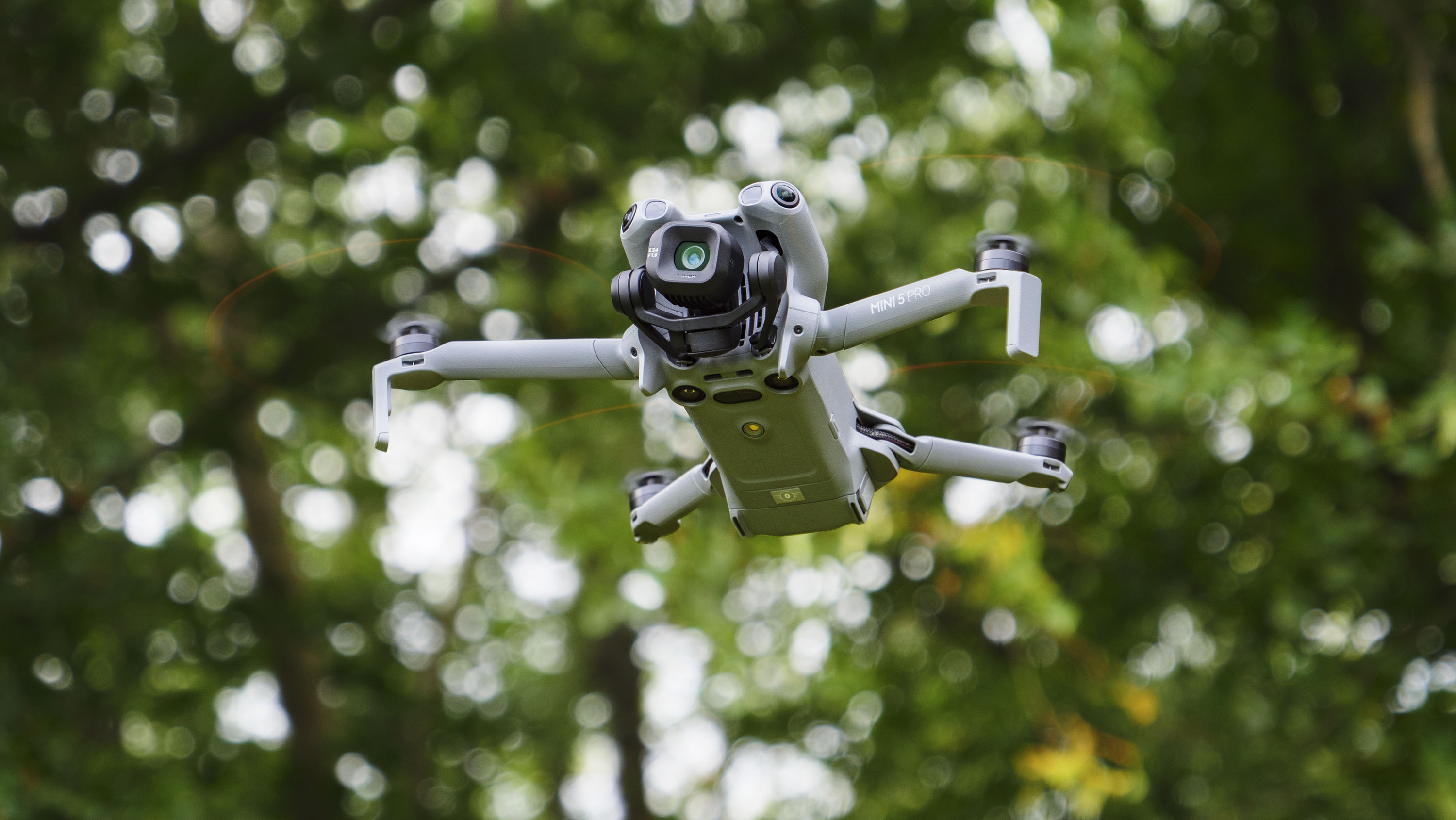 DJI Mini 5 Pro in flight with trees in the background